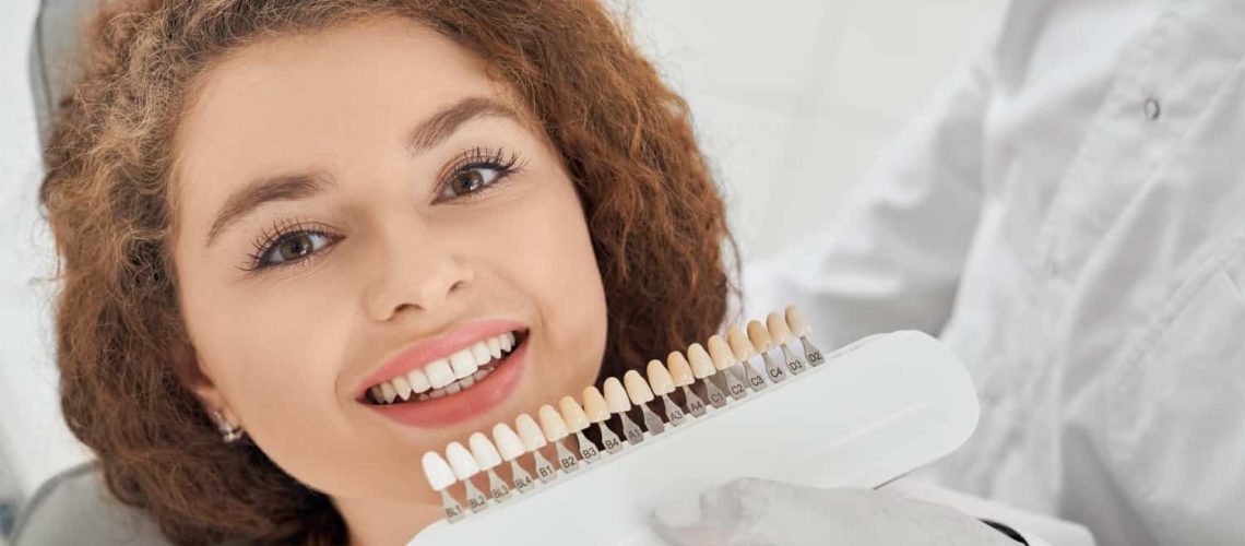Woman smiling while make dentist keeping teeth color range